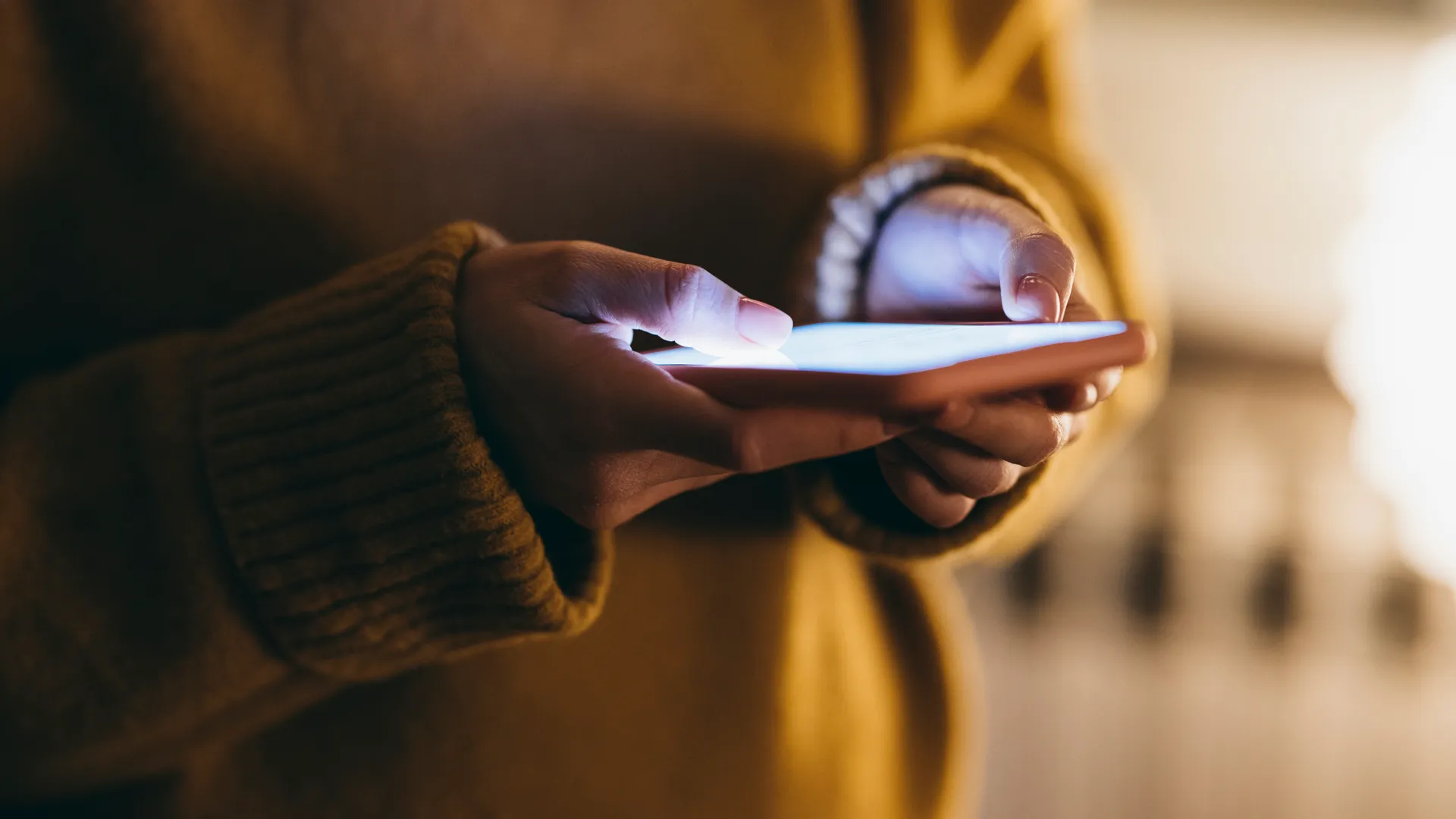 Hand med telefon gul tröja.webp